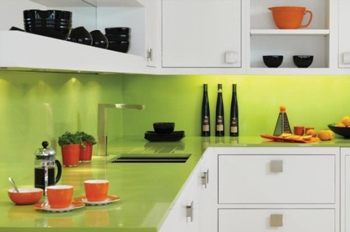 Die Arbeitsplatte und die Schürze eines hellen Limettenschattens sehen in Kombination mit weißen Küchenfronten und orangefarbenem Geschirr großartig aus.